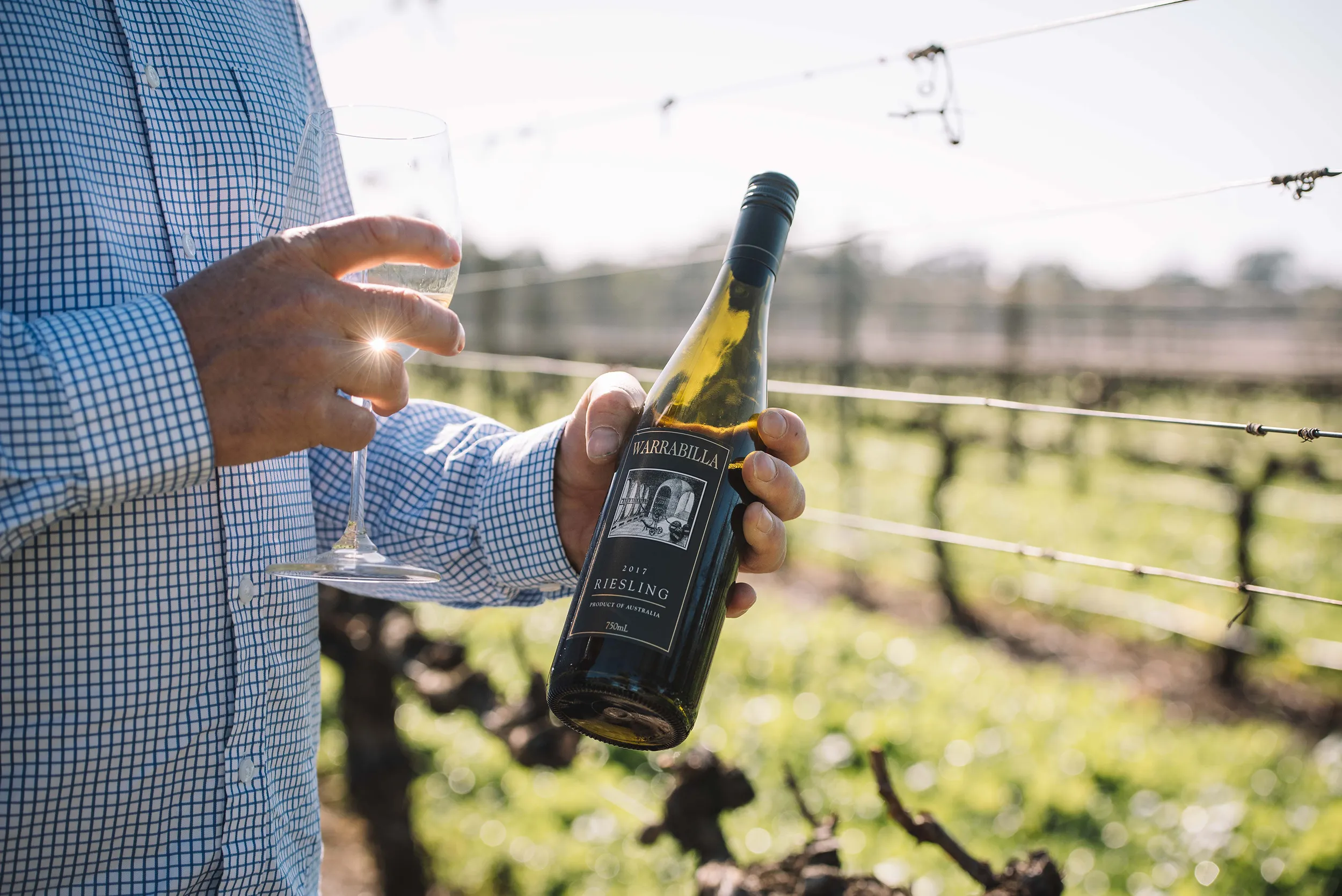 Person holding a bottle of Warrabilla wine and a glass